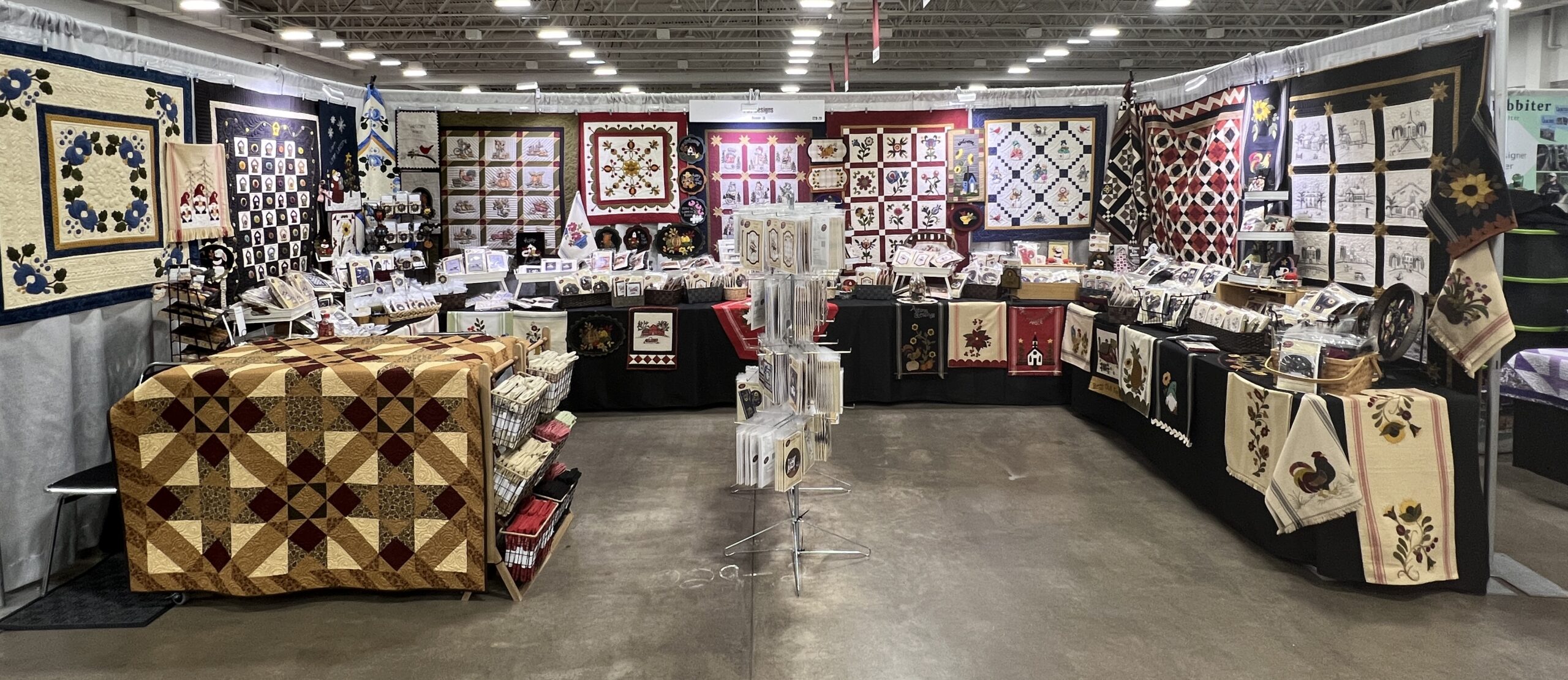 Booth set up with earth toned quilt, fabrics, and more