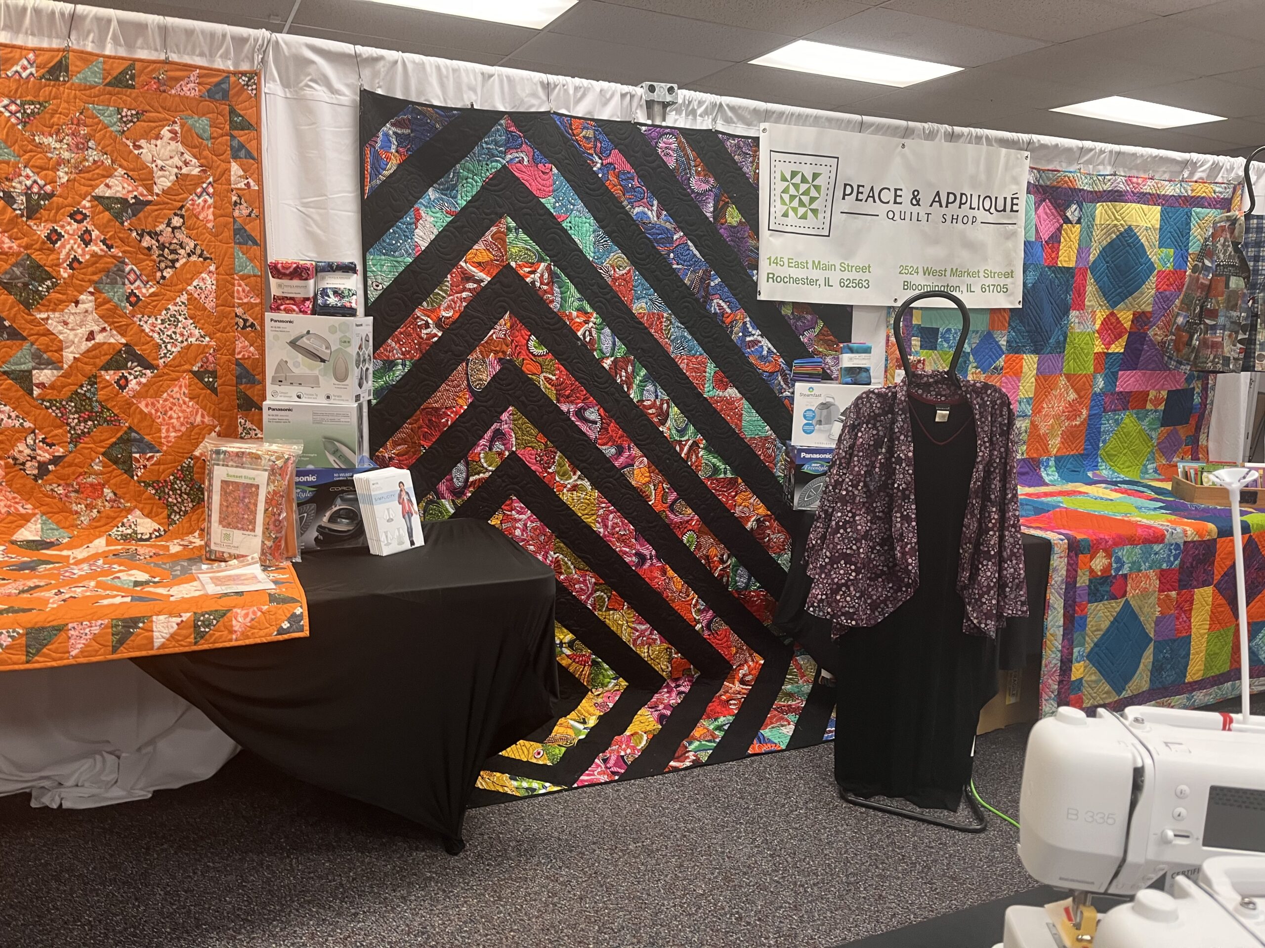 Peace & Appliqué vendor booth with quilts, wearables, notions